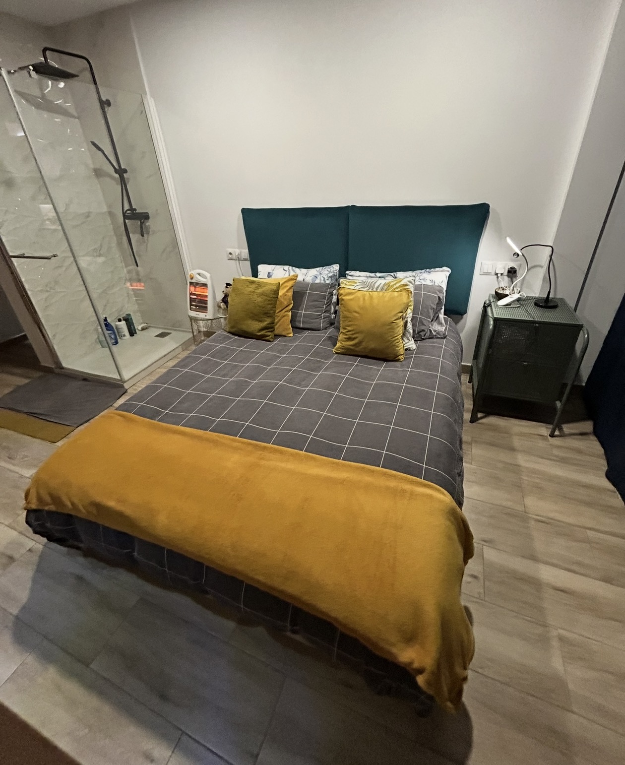 Double bedroom with green headboard and shower area